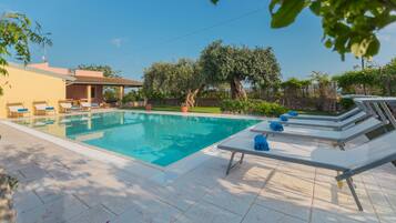 Relax by the rectangular pool surrounded by a tiled deck and lounge chairs.