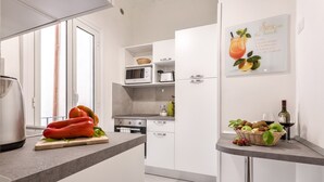 A modern kitchen with white cabinets, a microwave, a kettle, and a fruit basket on the counter. - Grotta Pinta 3 | Spacious and elegant just few steps from Piazza Navona (Roma)