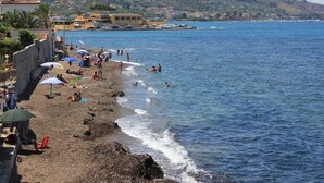 A beach with people sunbathing and swimming, a clear blue sea, and buildings in the background. - Last Minute-Jacuzzi & Sea View (Trabia)