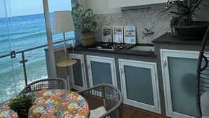 A modern kitchen with a view of the ocean, featuring a round table with a colorful tablecloth, a potted plant, and a ceiling with horizontal beams. - Last Minute-Jacuzzi & Sea View (Trabia)