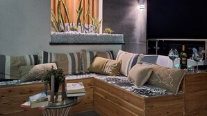 A modern living room with a sectional sofa, a glass coffee table, and a built-in planter with plants. - Last Minute-Jacuzzi & Sea View (Trabia)