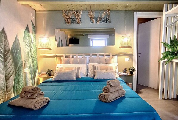 A bedroom with a large bed, a mirror above it, and a wall with leaf patterns. - Last Minute-Jacuzzi & Sea View (Trabia)