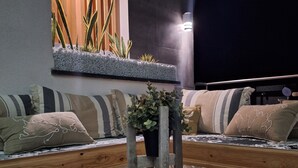 A modern outdoor seating area with a glass table, wooden benches, and potted plants. - Last Minute-Jacuzzi & Sea View (Trabia)