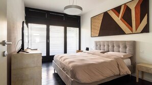 A modern bedroom with a large bed, a bedside table, a hanging light fixture, and a large abstract painting on the wall. - Terrace on the lake,private garage (Lugano)