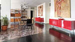 A modern living room with a dining area, a red console table, and a large abstract painting. - Terrace on the lake,private garage (Lugano)