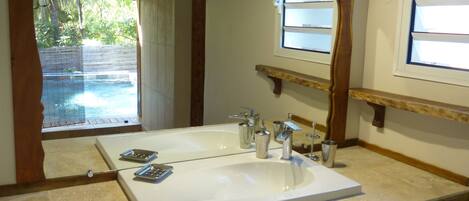 A bathroom with a large mirror, a white sink, and a wooden vanity.