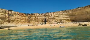 A coastal scene with layered cliffs, a sandy beach, and calm waters. - Luxury two BR pool view beside beach at Algarve's longest beach (Armacao de Pera)