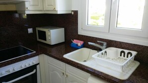 A kitchen with a stove, microwave, sink, and cabinets.
