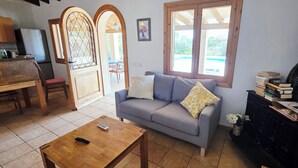 Un salon avec un canapé, une table en bois, un téléviseur et une bibliothèque.