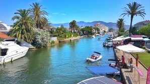 Ein Kanal mit Booten, Palmen und Gebäuden im Hintergrund.