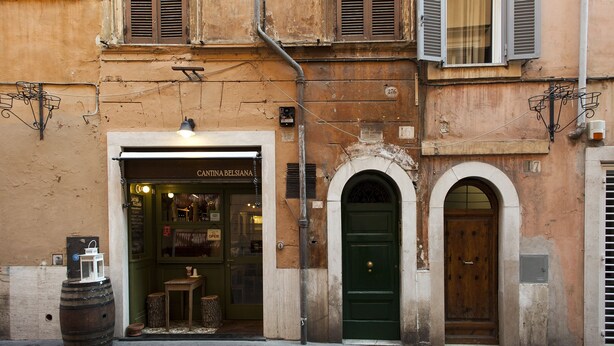 Un bâtiment dont la devanture porte l’inscription « CANTINA BELSIANA », avec une entrée en arc de cercle et une porte verte.