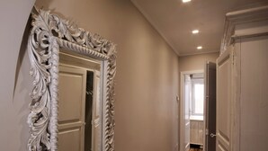 Un couloir orné de portes blanches richement décorées et d’un miroir aux motifs complexes.