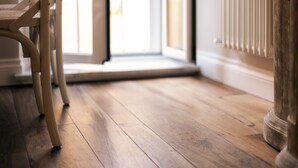Un plancher en bois mène à une porte près d’un radiateur.