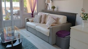 A modern living room with a glass coffee table, a sofa, and a white dresser. - Apartment in a small house in the heart of Cagnes-sur-Mer (Cagnes-Sur-Mer)