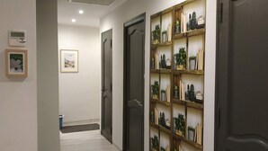 A hallway with wooden flooring, a wall-mounted shelf with plants and books, and a door at the end. - Apartment in a small house in the heart of Cagnes-sur-Mer (Cagnes-Sur-Mer)