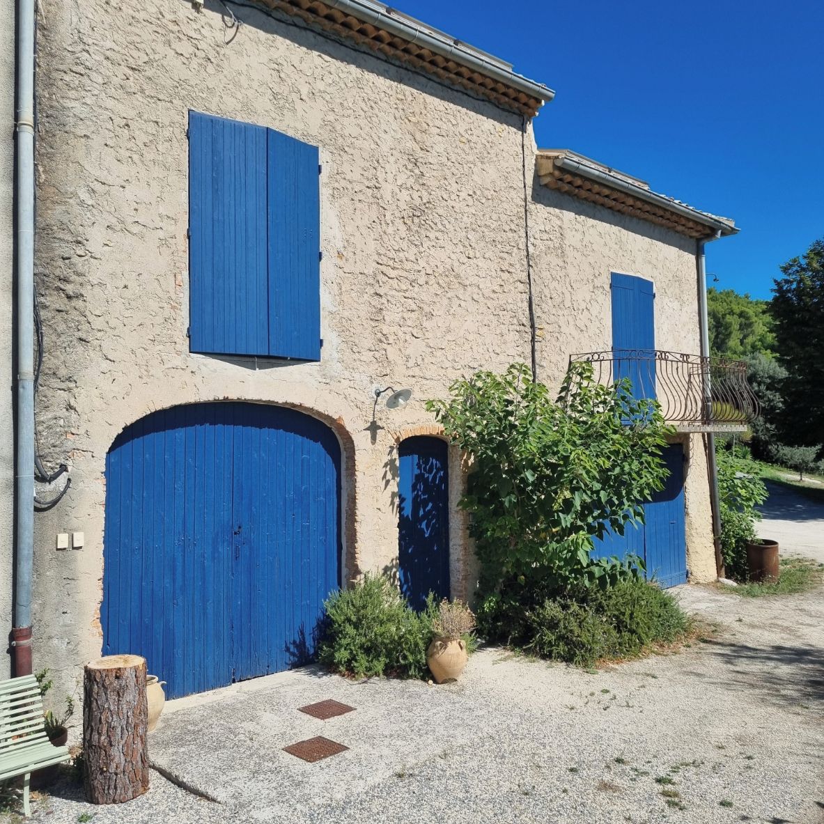 Un immeuble avec deux portes bleues et un petit balcon doté d’une rambarde en métal.