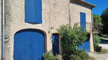 Un immeuble avec deux portes bleues et un petit balcon doté d’une rambarde en métal.