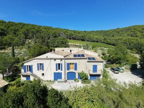 Un bâtiment à deux étages, doté d’un toit en pente, de volets bleus et de panneaux solaires.
