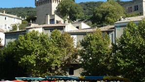 A historic building with a prominent tower and arches, surrounded by trees and market stalls. - La Roseraie des Côtes Gite 4 places avec Piscine possibility 2 more beds (Vinsobres)