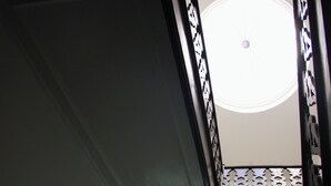 Uitzicht vanuit een raam in een gebouw, naar beneden een trap met een moderne lamp aan de muur.