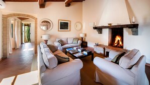 A living room with a fireplace, sofas, a coffee table with books, and a stone fireplace surround.