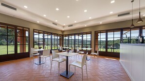 A spacious dining area with large windows, multiple tables, and chairs.