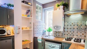 A compact kitchen with a microwave, a kettle, a sink, and a dishwasher.