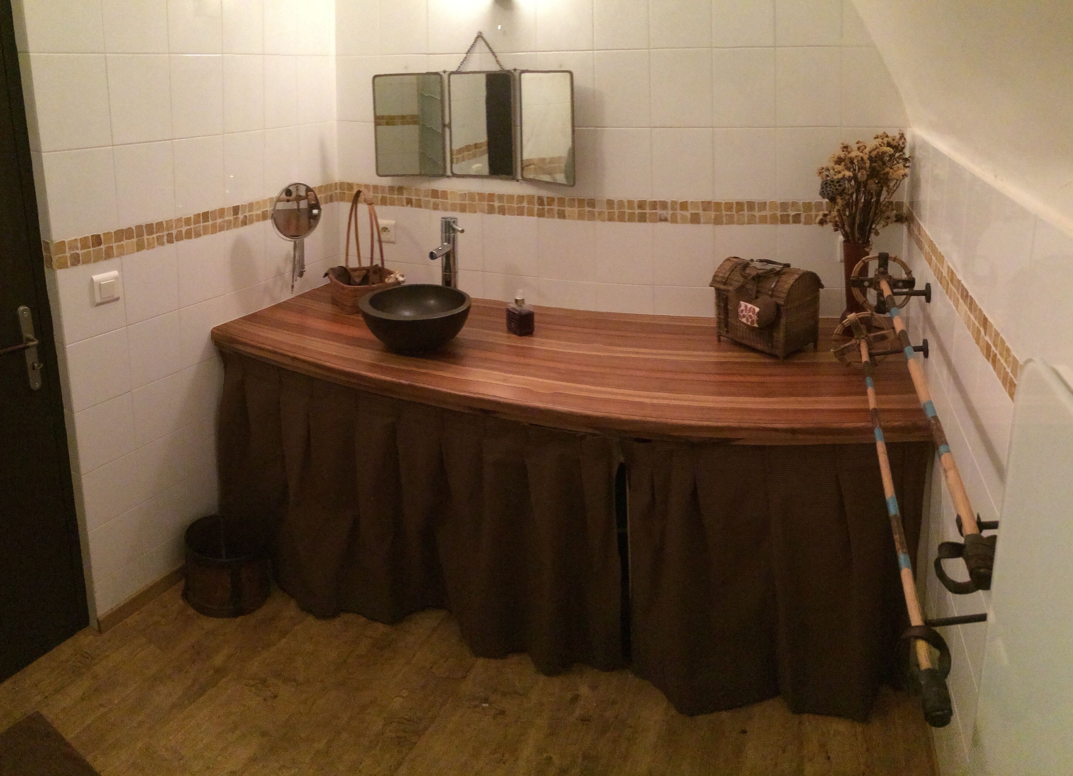 A bathroom with a wooden vanity, a mirror, a sink, and a towel rack.