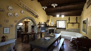 Un intérieur rustique avec un plafond en bois, une cheminée en pierre, une table à manger et un canapé.