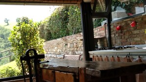 Une cuisine rustique avec un mur en pierre, une table en bois et une cuisinière à gaz.