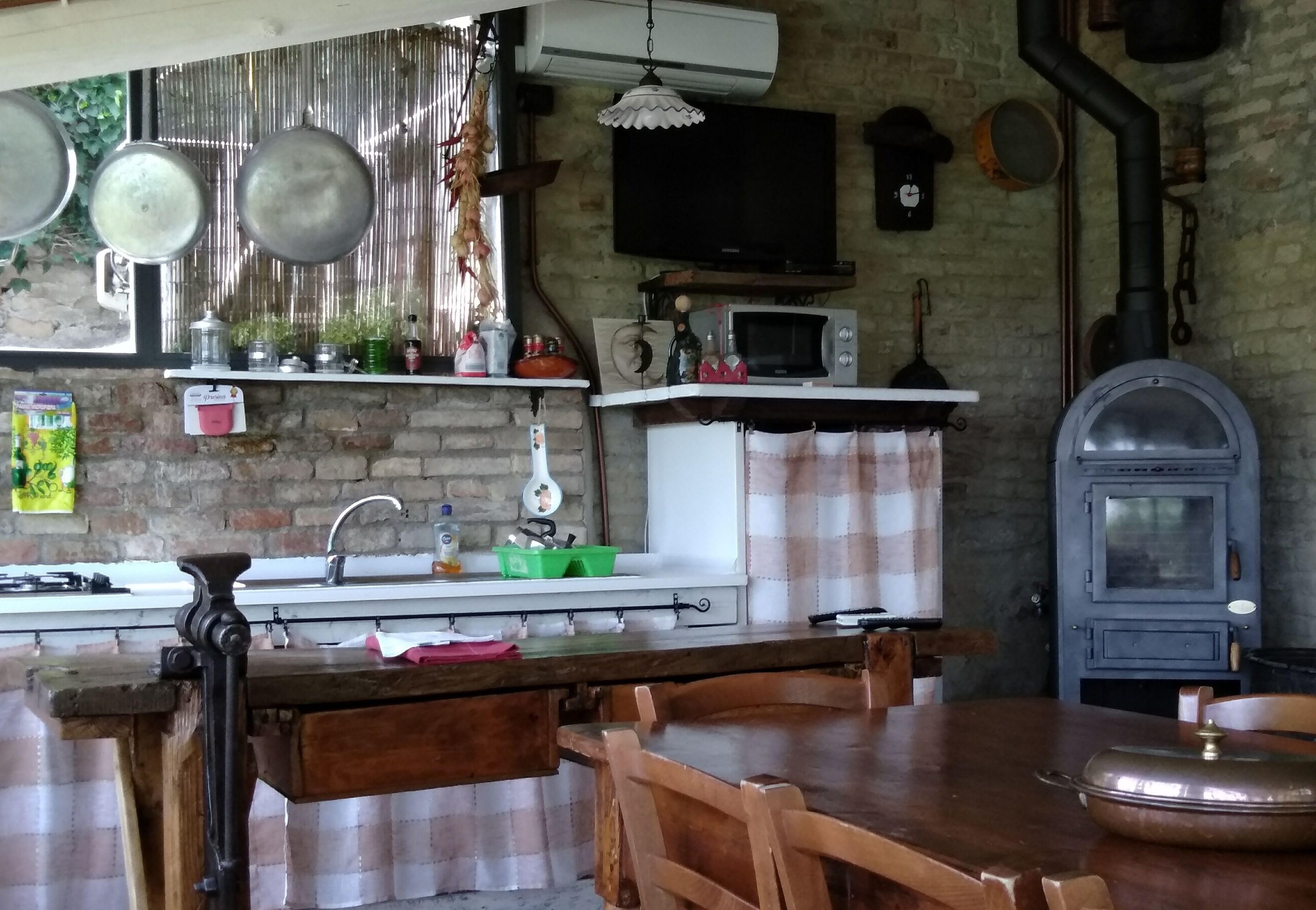 A rustic kitchen with a brick wall, a wooden table, and a vintage oven.