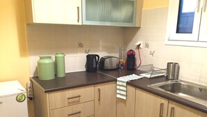 Eine Küche mit Holzschränken, einer Mikrowelle, einem Wasserkocher, einem Toaster und einem Spülbecken.