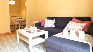 Ein Wohnzimmer mit einer Couch, einem Couchtisch und einem Essbereich, der durch einen offenen Durchgang sichtbar ist.