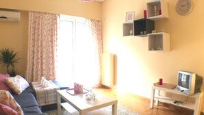 Ein Wohnzimmer mit einer Couch, einem Couchtisch, einem Fernseher auf einem Schrank und einem gemusterten Teppich.