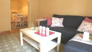 Ein Wohnzimmer mit einem weißen Couchtisch, einem dunklen Sofa und einem gemusterten Teppich.