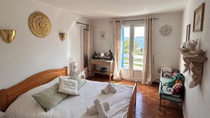 A bedroom with a wooden bed, a desk, and a view of the outdoors. - Cosy, quiet villa 150 metres from the sea and swimming pool Tennis included (Porto-Vecchio)