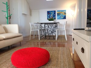 Relax in a stylish living space with a sofa, dining area, and mounted TV.