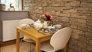 A dining table with tea set and chairs in a room with stone walls and a window.
