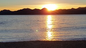 Un tramonto sul mare calmo con montagne sullo sfondo.