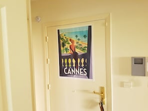 Una puerta con un cartel del Festival de Cine de Cannes, un timbre y un panel de seguridad.