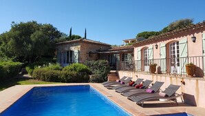A poolside area with lounge chairs and a stone building with a tiled roof. - Superb Villa with Private Pool and Sea Views (Sainte-Maxime)