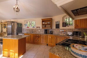 A kitchen with granite countertops, wooden cabinets, a stainless steel refrigerator, a built-in oven, and a gas stove.