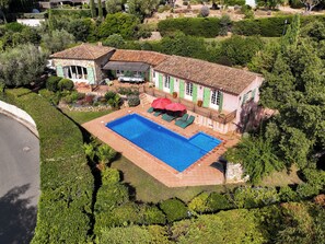 A residential property with a swimming pool, outdoor seating, and a well-maintained garden.