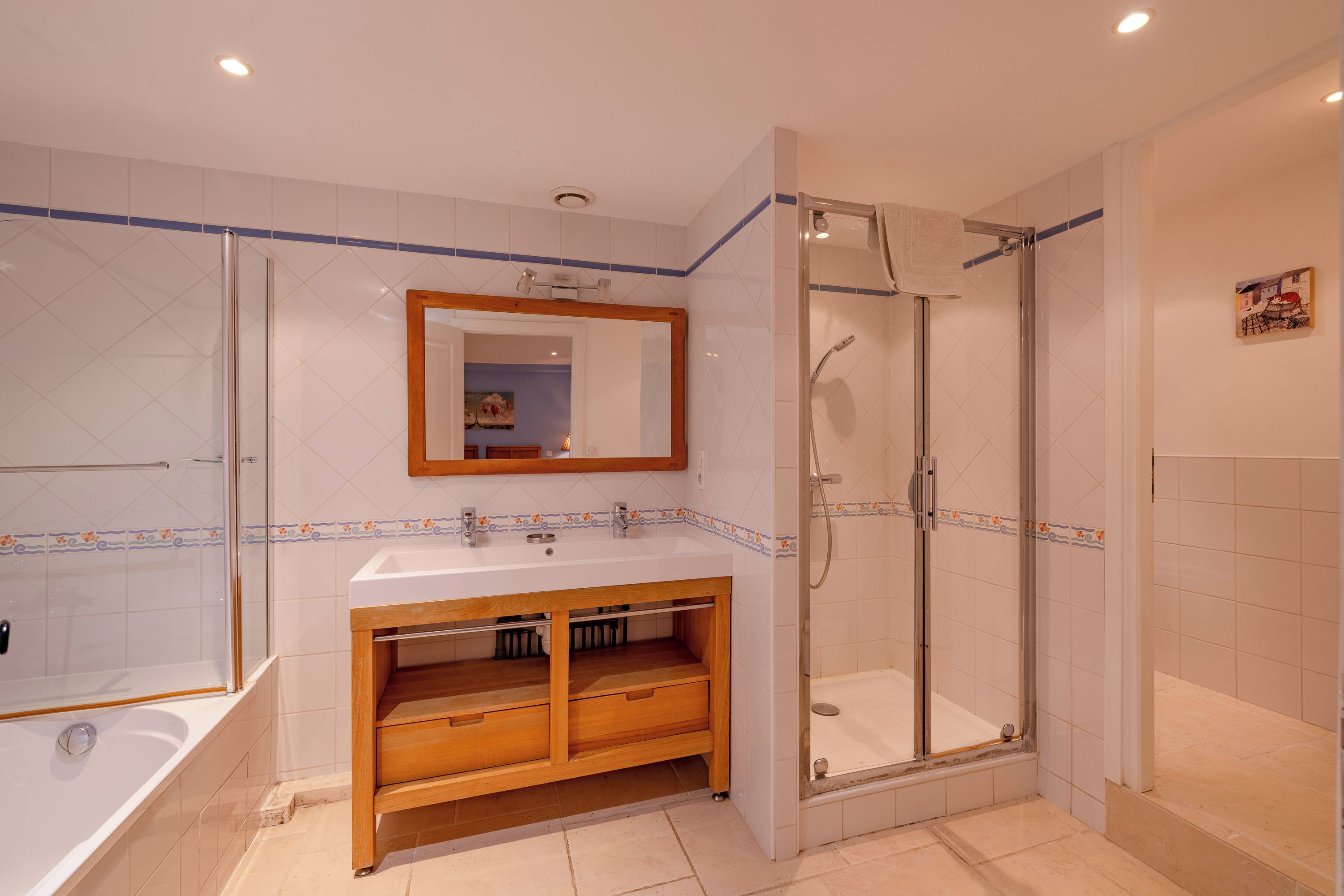 A modern bathroom with a glass-enclosed shower, a wooden vanity, and a large mirror.