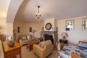 A living room with a fireplace, a sofa, a coffee table, and a dining area with a table and chairs.