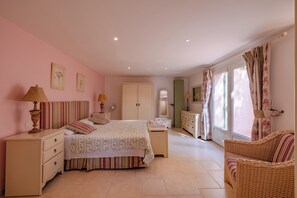 A bedroom with a double bed, bedside tables, a dresser, a mirror, and a window with curtains.