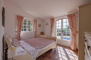 A bedroom with a bed, a bedside table, a lamp, and a dresser.