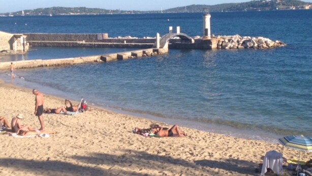 A beach with people sunbathing and swimming, a lighthouse, and a rocky breakwater. - Superb Villa with Private Pool and Sea Views (Sainte-Maxime)