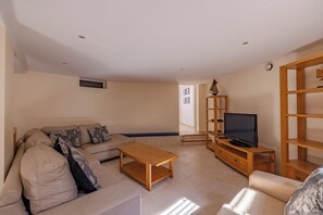A living room with a sofa, coffee table, TV stand, and bookshelf.