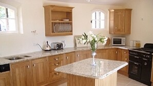 A kitchen with wooden cabinets, a granite countertop island, a microwave, and a stove. - Superb Villa with Private Pool and Sea Views (Sainte-Maxime)